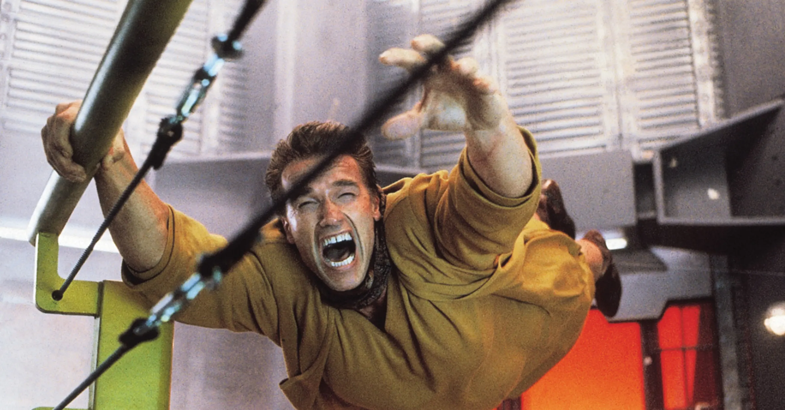 Arnold Schwarzenegger hängt an einer Stange und steht kurz davor in die Atmosphäre des Mars gezogen zu werden (Total Recall)
